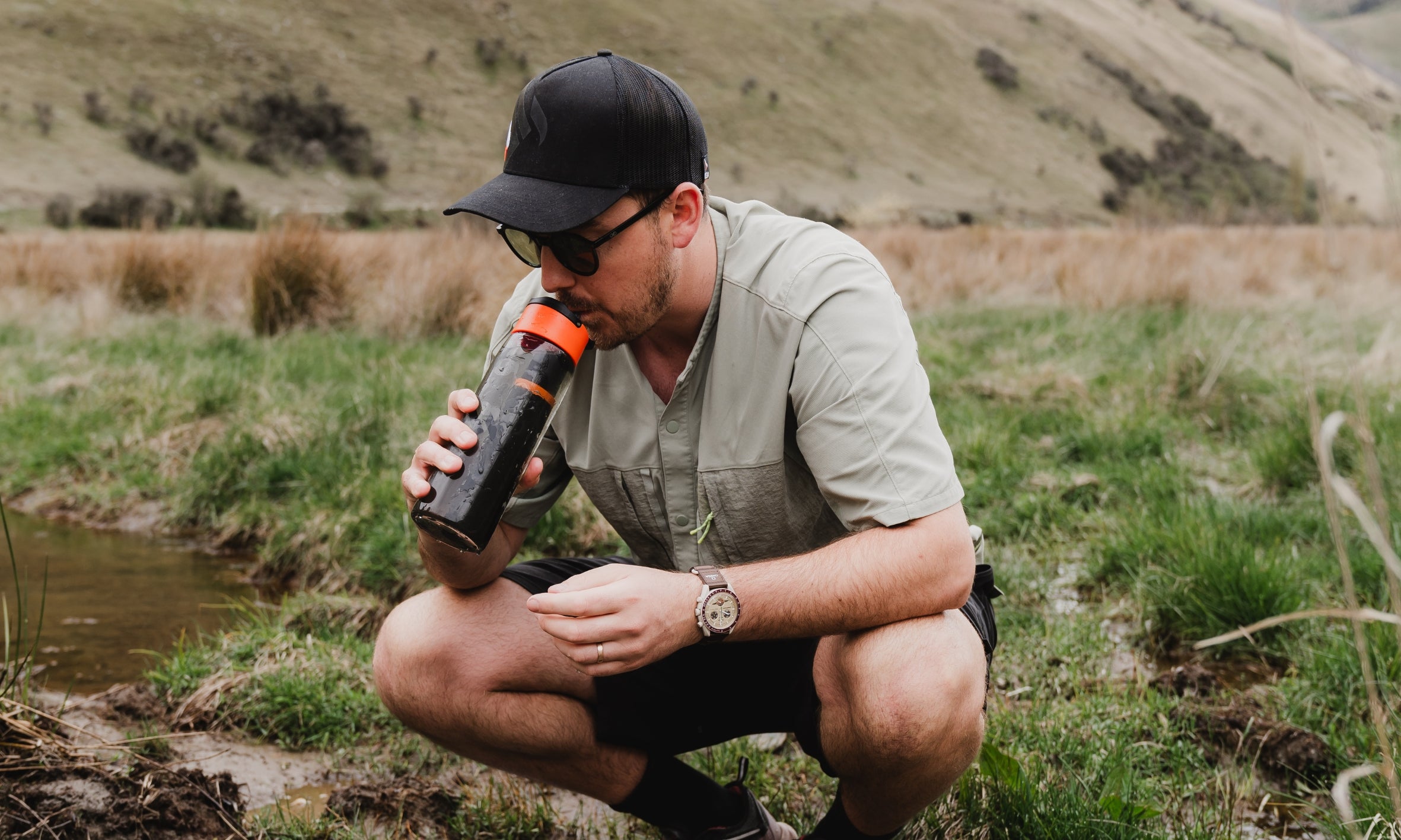Tramper filtering freshwater beside a New Zealand river