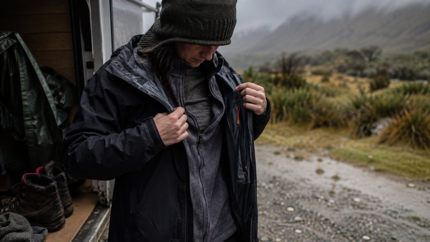 Tramper preparing waterproof layers in changeable New Zealand weather